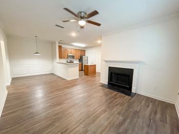An empty living room with a fireplace and a kitchen